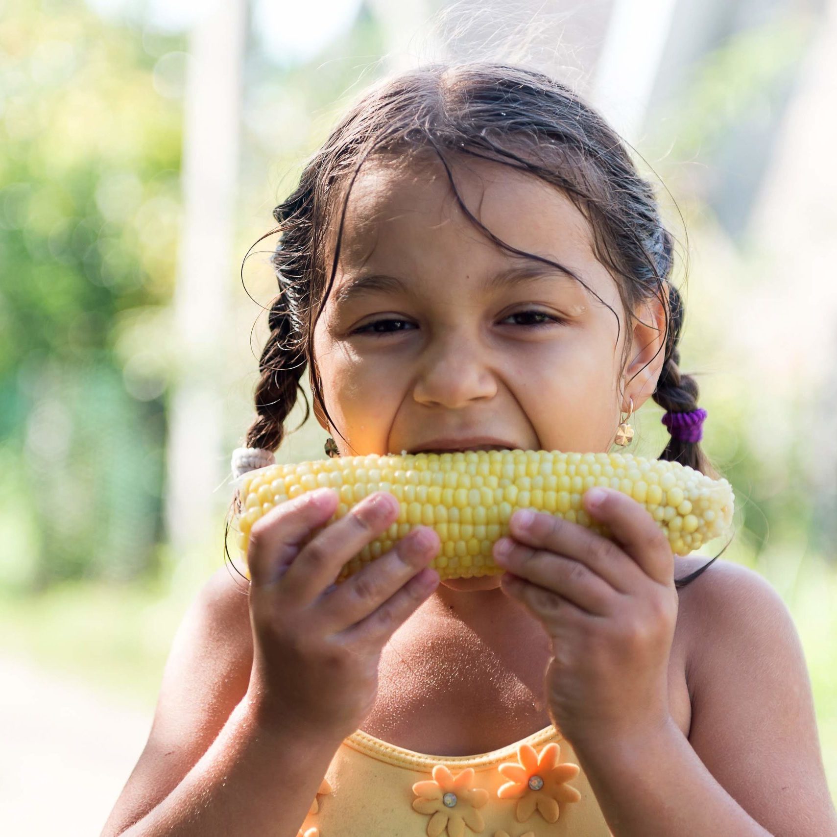 young girl eating an ear of corn