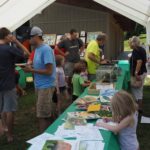 Picture of people gathered around display tables at event