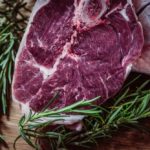 A cut of meat with herbs around it