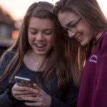 Picture of two teenage girls looking at a cell phone