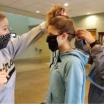 Picture of a young girl putting on a face covering