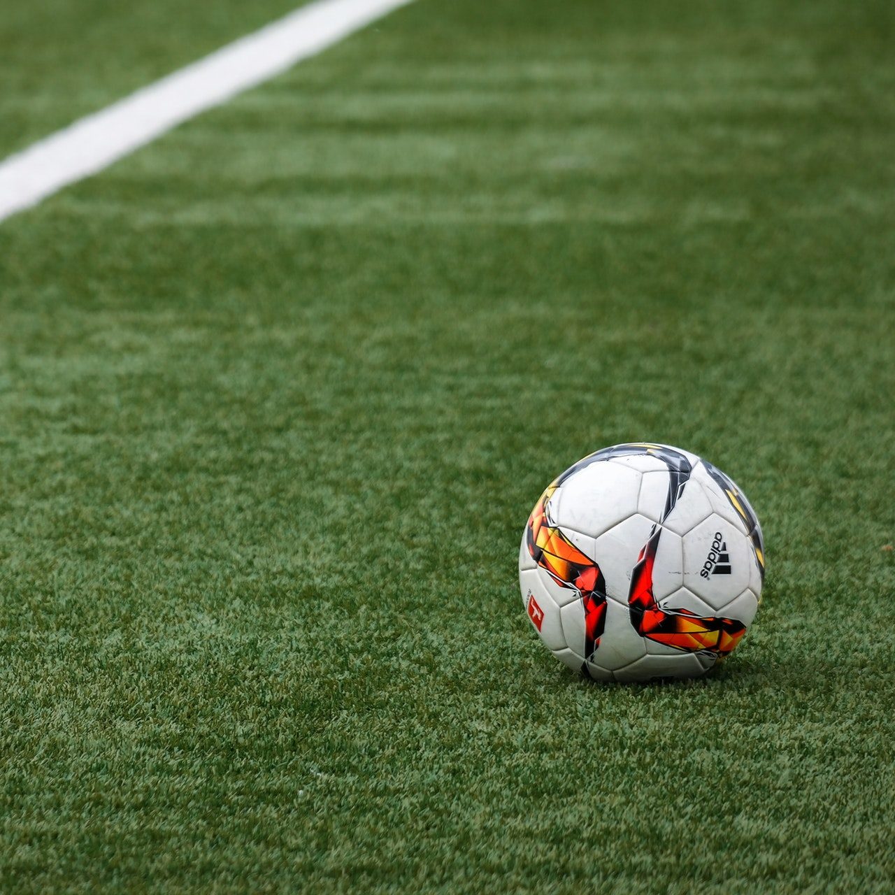 A lone soccer ball sits on a natural turf field 