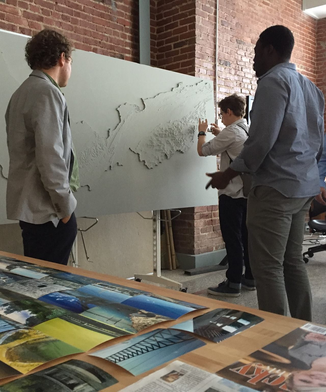 Three students talk over a 3 D map relating to a UT River Studio project 