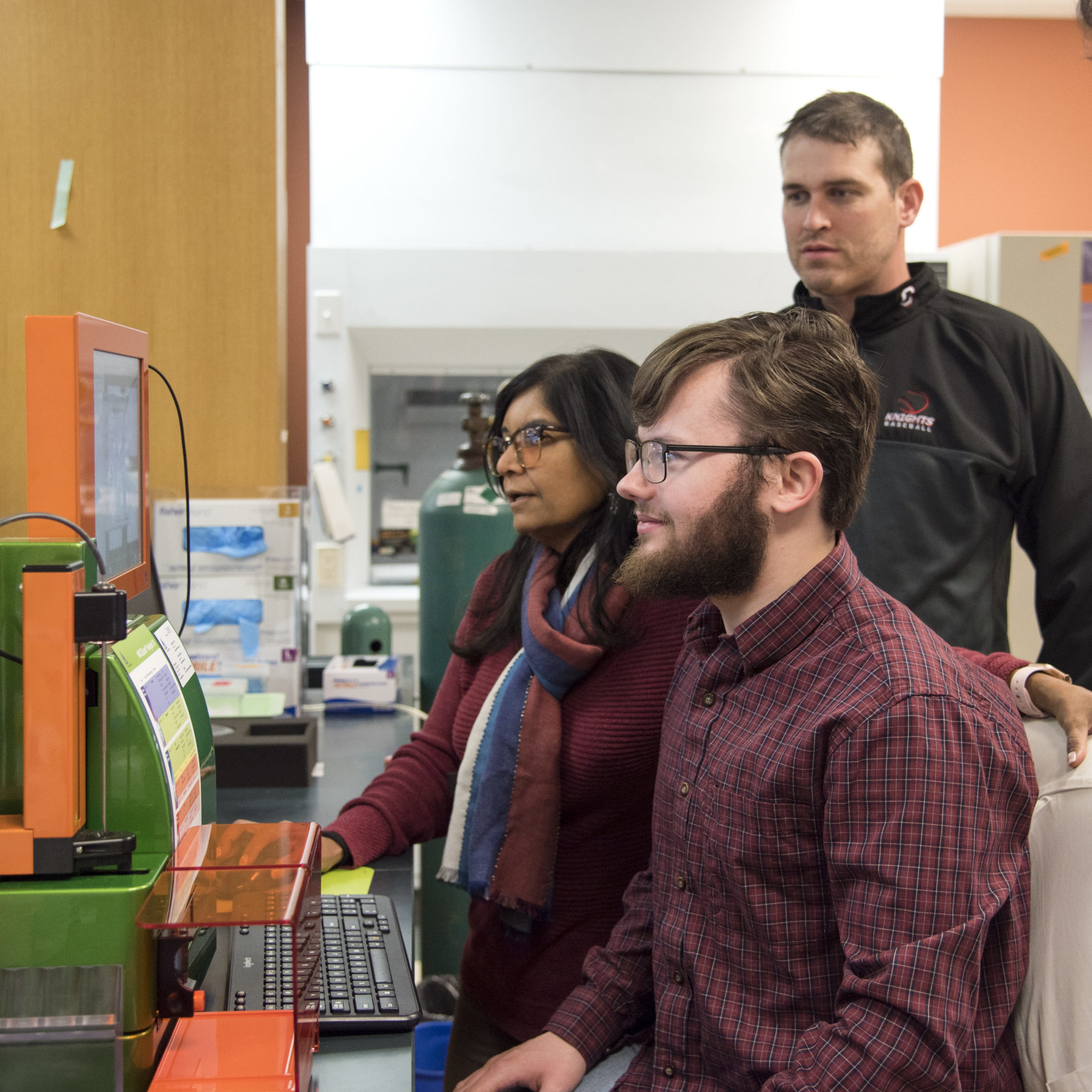 Omics hub scientist instruct graduate students on machinery in lab 