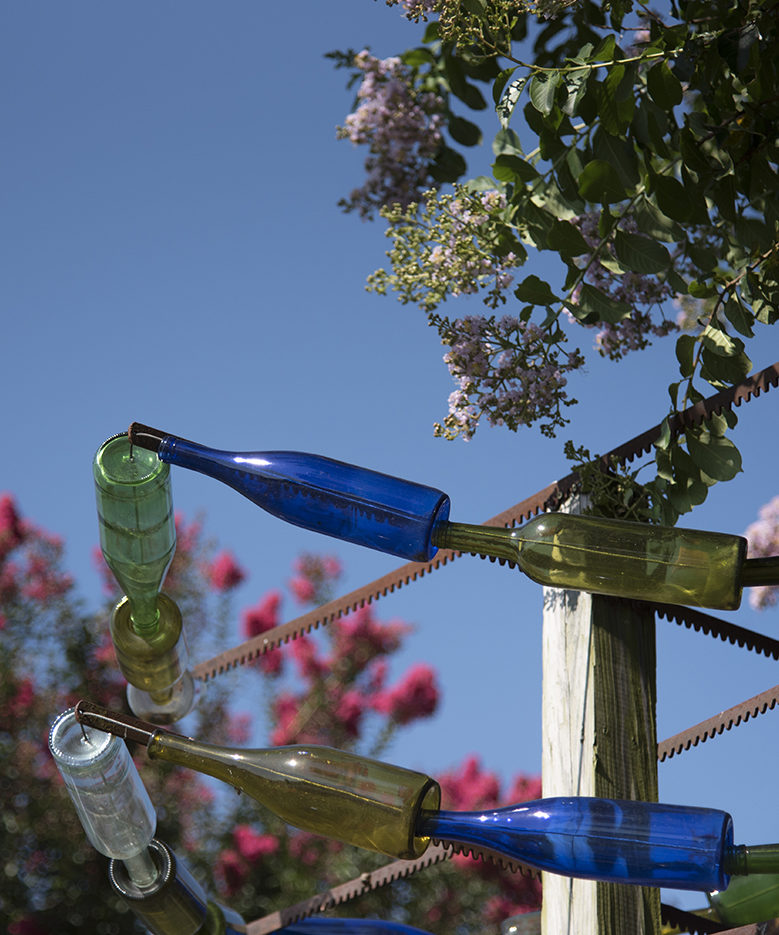 Glass bottle art is displayed against a hazy blue sky 